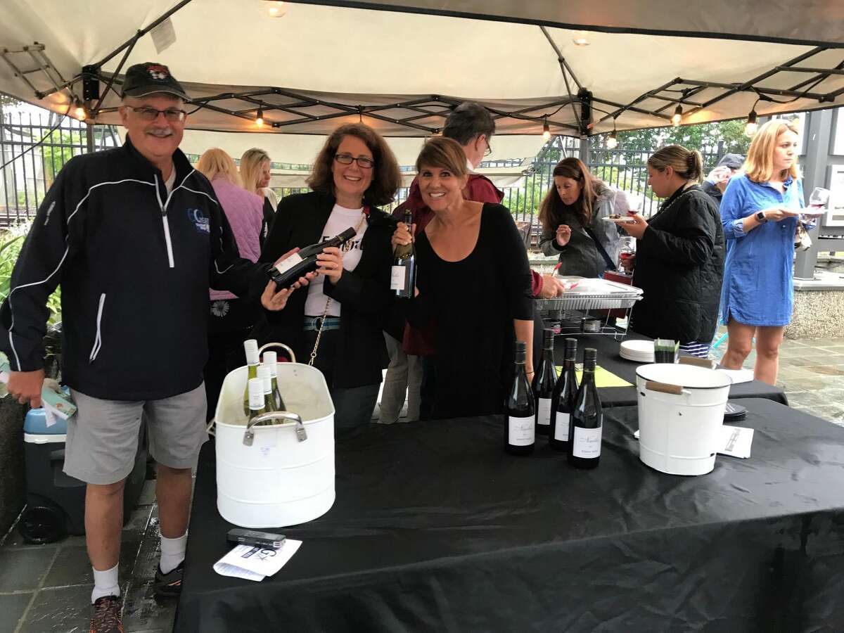 Attendees enjoy food donated by the Greek Spot Cafe & Grill and wine tasting with Gary Johnson, president and CEO of Milford United Way; and Kari Candelora and Lorie Lewis of the Milford Arts Council.
