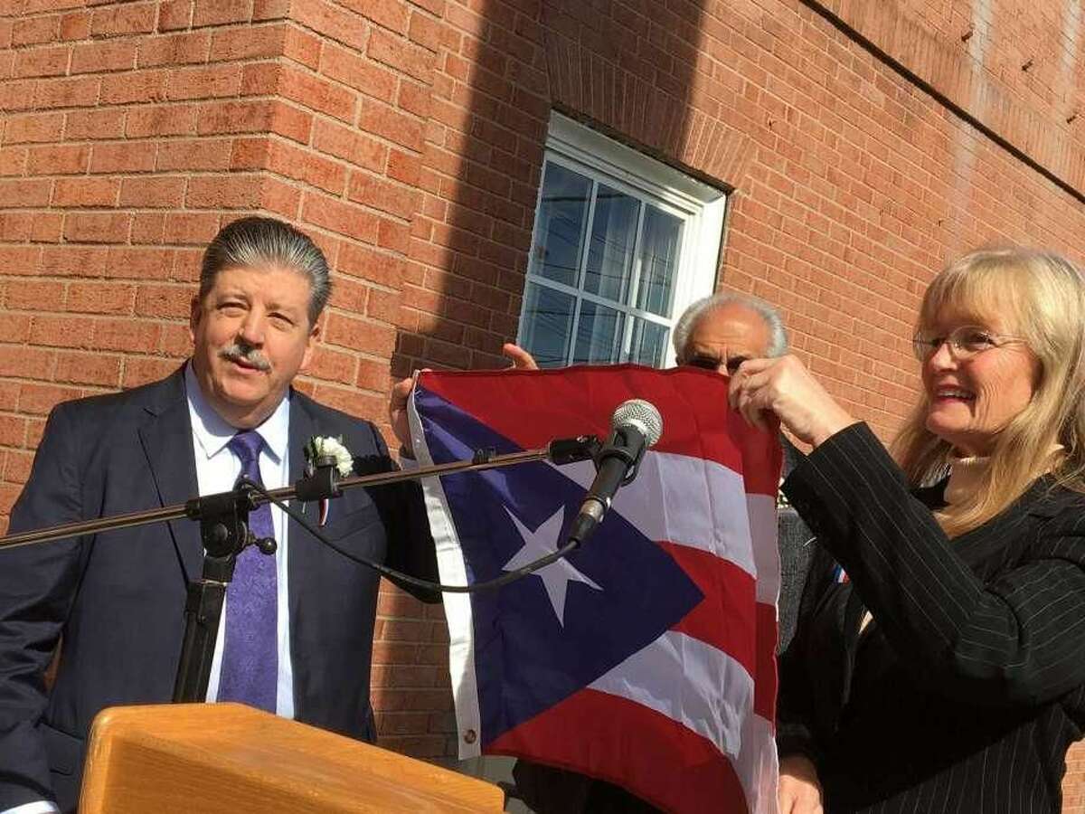 West Haven honored veterinarian Dr. Ralph Padilla on Friday, Oct. 19, as its first-ever Hispanic American of the Year. Mayor Nancy Rossi, right, presented Padilla, left, with the flag of Puerto Rico, as Master of Ceremonies Louis Esposito, Rossi’s executive assistant, looks on.