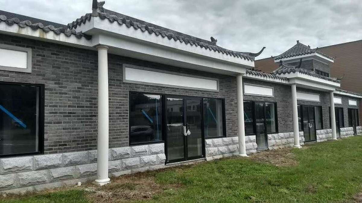 The owners of this marketplace under construction at 804 Boston Post Road have been fined $100 per day under the city's blight ordinance. The photo taken Thursday shows they removed the bulk of vegetation overgrowth that obscured the building for months.