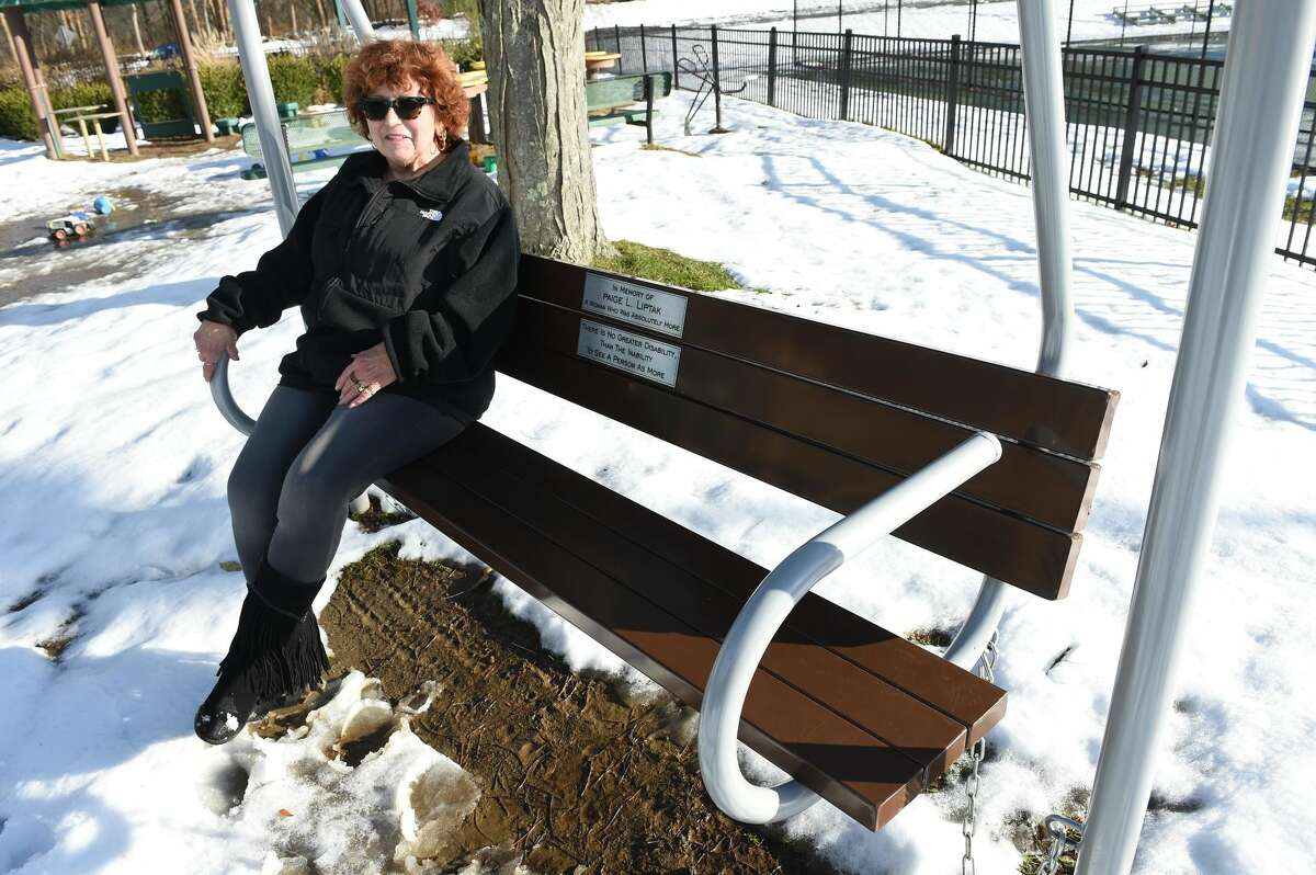 Former Milford animal control officer Pat Liptak sits on a memorial bench swing honoring her deceased daughter, Paige L. Liptak, at Bodie's Place playground in Eisenhower Park in Milford.