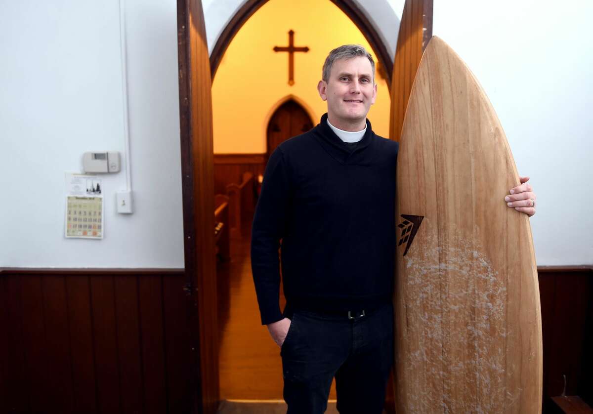 Rev. Matt Lindeman with one of his surfboards at St. Peter's Episcopal Church in Milford.