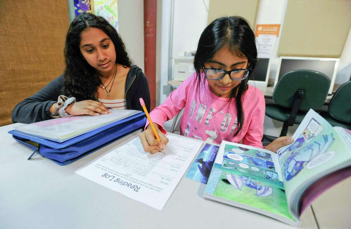 From left, Priyanka Umamahesnaran, a sophomore at Stamford High School who volunteers her time at Building One Community”s “Homework Club” assists Westover fifth-grader Sabrina Puluc in a reading assignment at B1C in Stamford on Tuesday. Puluc, who has been coming for after school help this past year, said that at home her family speaks Spanish, making it difficult for her mother to help her complete her daily homework. Spanish is the most common language after English that Stamford Public Schools students speak at home.