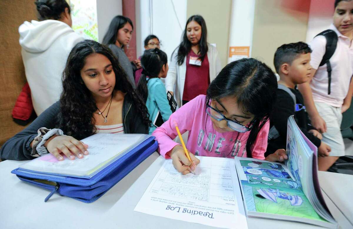 From left, Priyanka Umamahesnaran, a sophomore at Stamford High School who volunteers her time at Building One Community's "Homework Club" assists Westover fifth-grader Sabrina Puluc in a reading assignment at B1C in Stamford, Connecticut on Oct. 8, 2019. Puluc, who has been coming for after school help this past year, said that at home her family speaks Spanish, making it difficult for her mother to help her complete her daily homework. Spanish is the most common language after English that Stamford Public Schools students speak at home.