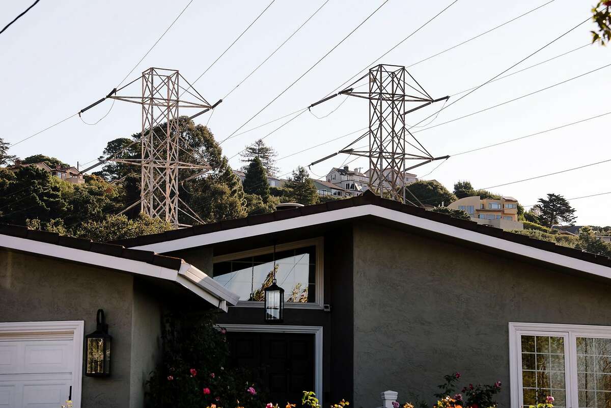 Power lines and towers are seen above homes near the Montclair neighborhood where power is out, in Oakland, California, on Friday, Oct. 10, 2019. PG&E planned power outages affected parts of Oakland and Alameda County as the utility fights to stave off wildfires that can be caused by high winds hitting their power lines.