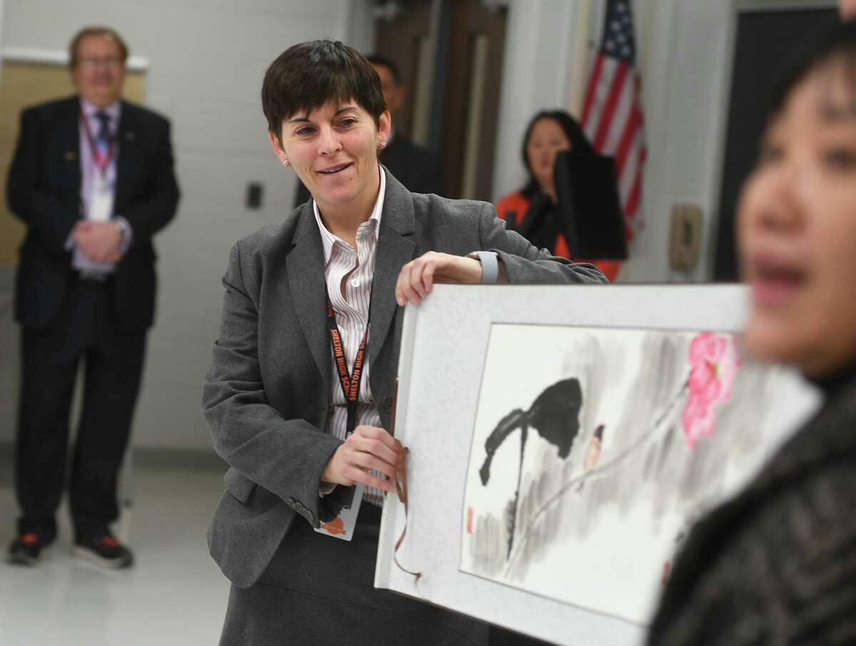 Shelton High Headmaster Beth Smith, left, unfurls a Chinese painting, a gift from Jian Ping High School, Shelton's sister school in Shanghai, China, during a visit by students from the school to Shelton, Conn. on Tuesday, January 29, 2019.