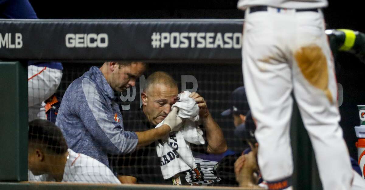 An injured staff member is escorted out of the Astros dugout after being struck by a foul ball hit by Houston Astros left fielder Michael Brantley (23) during the fifth inning of Game 2 of the American League Championship Series at Minute Maid Park on Sunday, Oct. 13, 2019, in Houston.