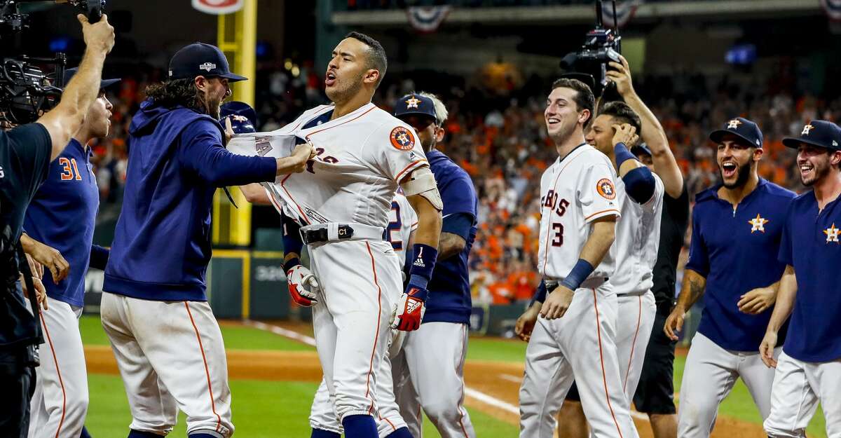 Houston Astros center fielder Jake Marisnick (6) rips the jersey off of Houston Astros shortstop Carlos Correa (1) as they celebrate Correa's walk off home run in the eleventh inning to win Game 2 of the American League Championship Series at Minute Maid Park on Sunday, Oct. 13, 2019, in Houston.