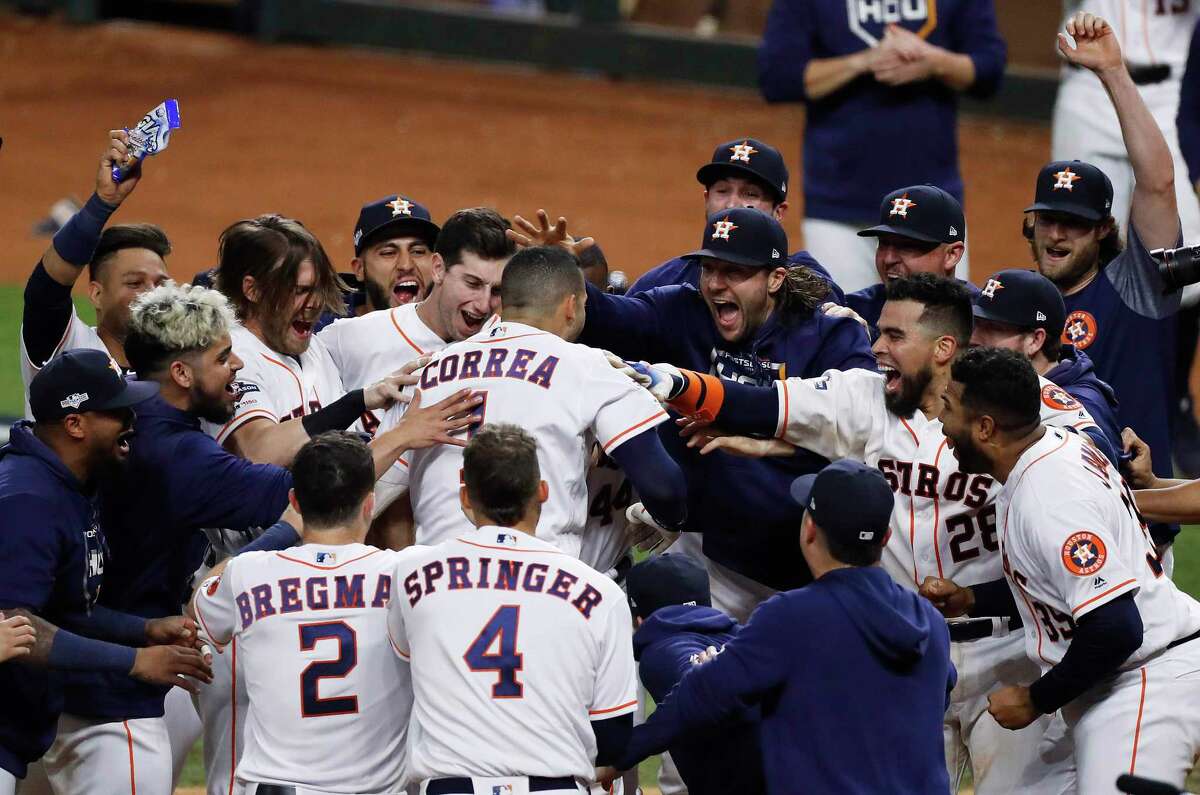 Houston Astros shortstop Carlos Correa is mobbed by his teammates at home plate after hitting a walk-off home run off New York Yankees pitcher J.A. Happ during the 11th inning in Game 2 of baseball's American League Championship Series in Houston on Sunday, Oct. 13, 2019.