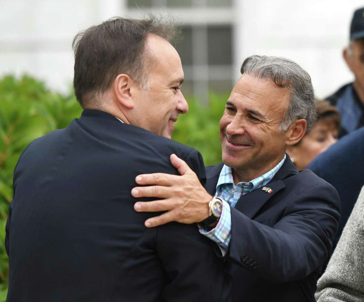 State Rep. Fred Camillo hugs Greenwich First Selectman Peter Tesei, left, during the St. Lawrence Society's Columbus Day flag-raising ceremony at Town Hall in Greenwich, Conn. Monday, Oct. 14, 2019. Camillo will be sworn in as the new first selectman on Dec. 1.