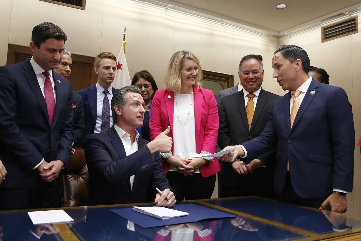 California Gov. Gavin Newsom, seated, gives a thumbs up to Assemblyman Todd Gloria, D-San Diego, right, after signing Gloria's measure that prohibits the sale of firearms and ammunition at the Del Mar Fairgrounds, during a ceremony the Capitol in Sacramento, Calif., Friday, Oct. 11, 2019. Gloria's measure was one of more than a dozen gun violence prevention bills the governor signed Friday. (AP Photo/Rich Pedroncelli)