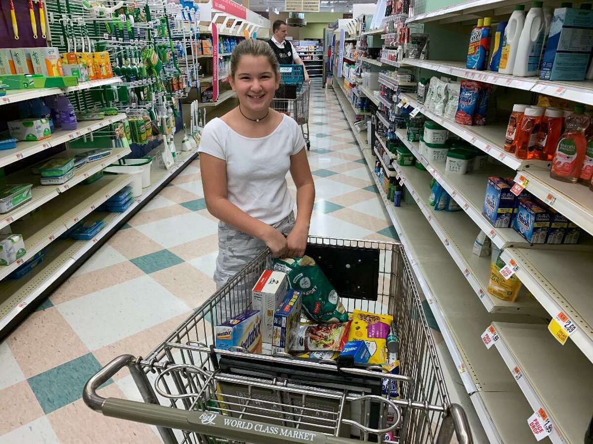 Kaelyn DiMartino, 12, of Derby smiles after dropping an armful of cereal, fruit snacks and ‘other good things” in to her father, Joe’s cart at the Big Y Supermarket in Ansonia Monday. The store announced a 50 percent off all item sale as it prepares to close. A new Big Y World Class Market will open Nov. 7 in Derby.