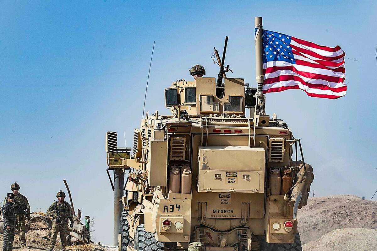 (FILES) In this file photo taken on October 6, 2019 a US soldier sits atop an armoured vehicle during a demonstration by Syrian Kurds against Turkish threats next to a base for the US-led international coalition on the outskirts of Ras al-Ain town in Syria's Hasakeh province near the Turkish border. - All US troops in northern Syria have been ordered to leave the country in the face of Turkey's attacks on Kurds in the region, a US official said October 14, 2019. Some 1,000 troops will vacate the country, leaving behind only a small contingent of 150 in the southern Syria base at Al Tanf, the official said, one day after President Donald Trump ordered the evacuation."We are executing the order," the official told AFP. (Photo by Delil SOULEIMAN / AFP) (Photo by DELIL SOULEIMAN/AFP via Getty Images)
