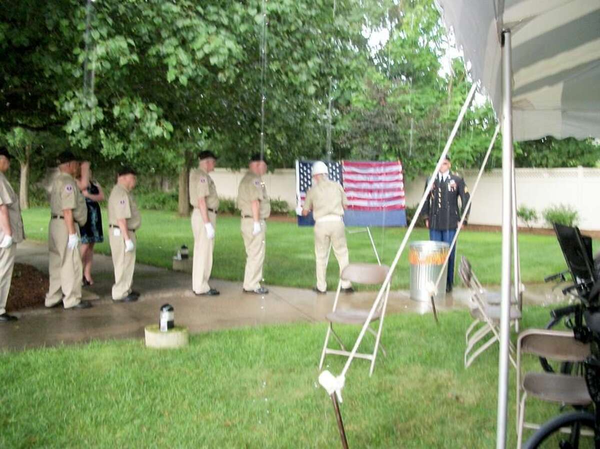 Photo by Lynn Fredricksen Members of Antique Veterans of Meriden retire the flag in the midst of a sudden downpour during a ceremony to honor veterans who are residents at Arden Courts.