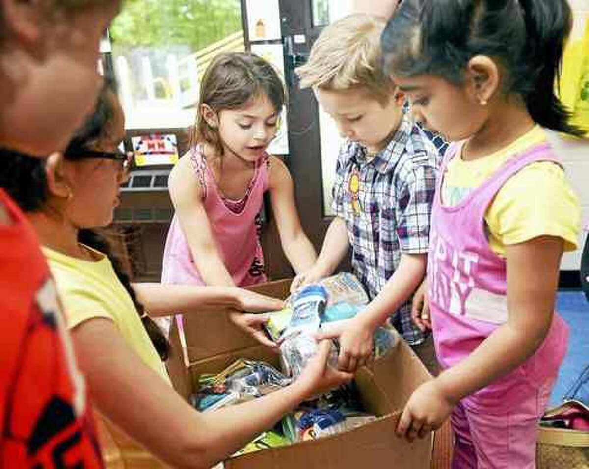 Arnold Gold — New Haven Register Kindergarten classmates help Jeremy Gagne, second from right, load Blessing Bags into boxes at West Woods School in Hamden. The Blessing Bags are for homeless veterans.