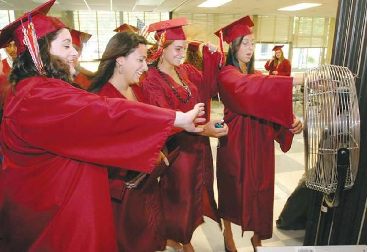 Photo by Mara Lavitt North Haven High School graduates left to right Caitlin Bracale, Susan Gambardella, Maria Sanzari and Tori Burr keep cool by a fan while waiting to line up for commencement.