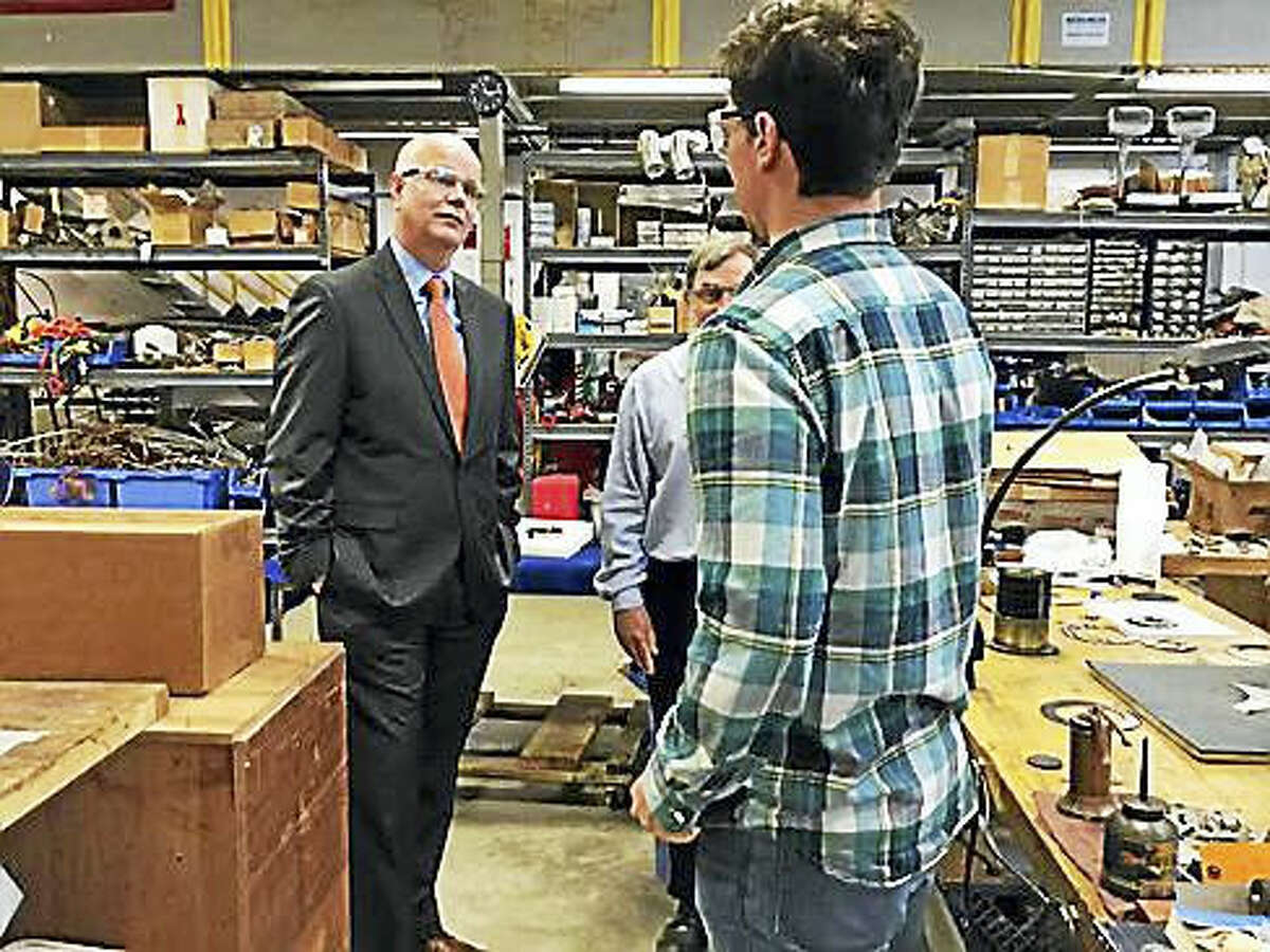 Kevin Lembo at Precision Combustion Thursday talks to workers.