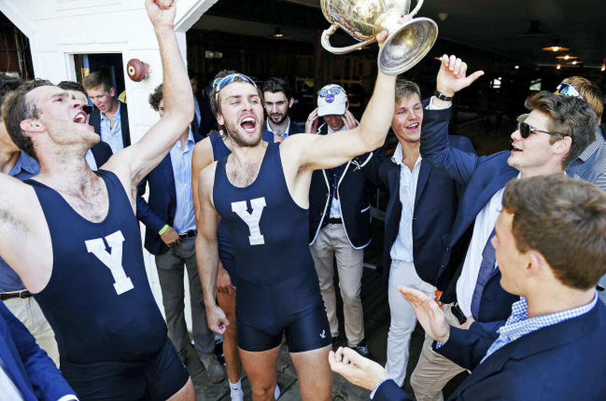 Yale bowman Ollie Wynne-Griffith hoists the Sexton Cup as the Bulldogs celebrate the heavyweight crew team’s win at the annual Harvard/Yale regatta in Ledyard.