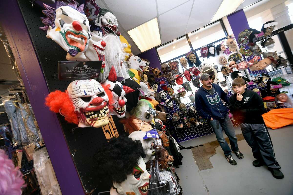 Pete Tarini (center) and his son, Luke, 10, of Naugatuck walk past scary clown masks in the Spooky Town Halloween Superstore in Orange on October 1, 2017. Arnold Gold / Hearst Connecticut Media
