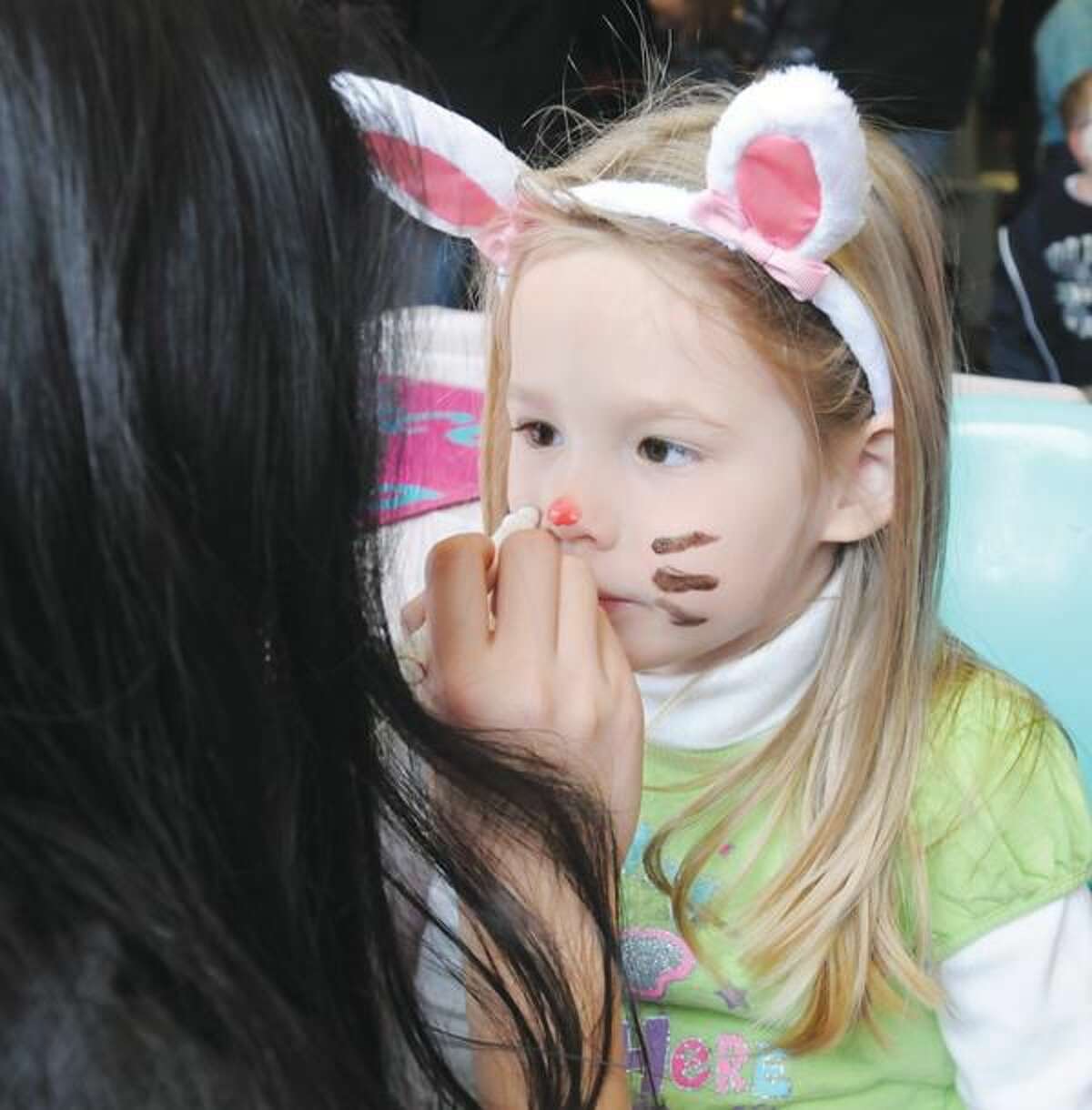 Photo by Mara Lavitt Hien Ngo of North Haven, left, paints Alana Schweinsburg, age 4, of Wallingford, to match her rabbit ears at North Haven's annual Easter Eggstravaganza.