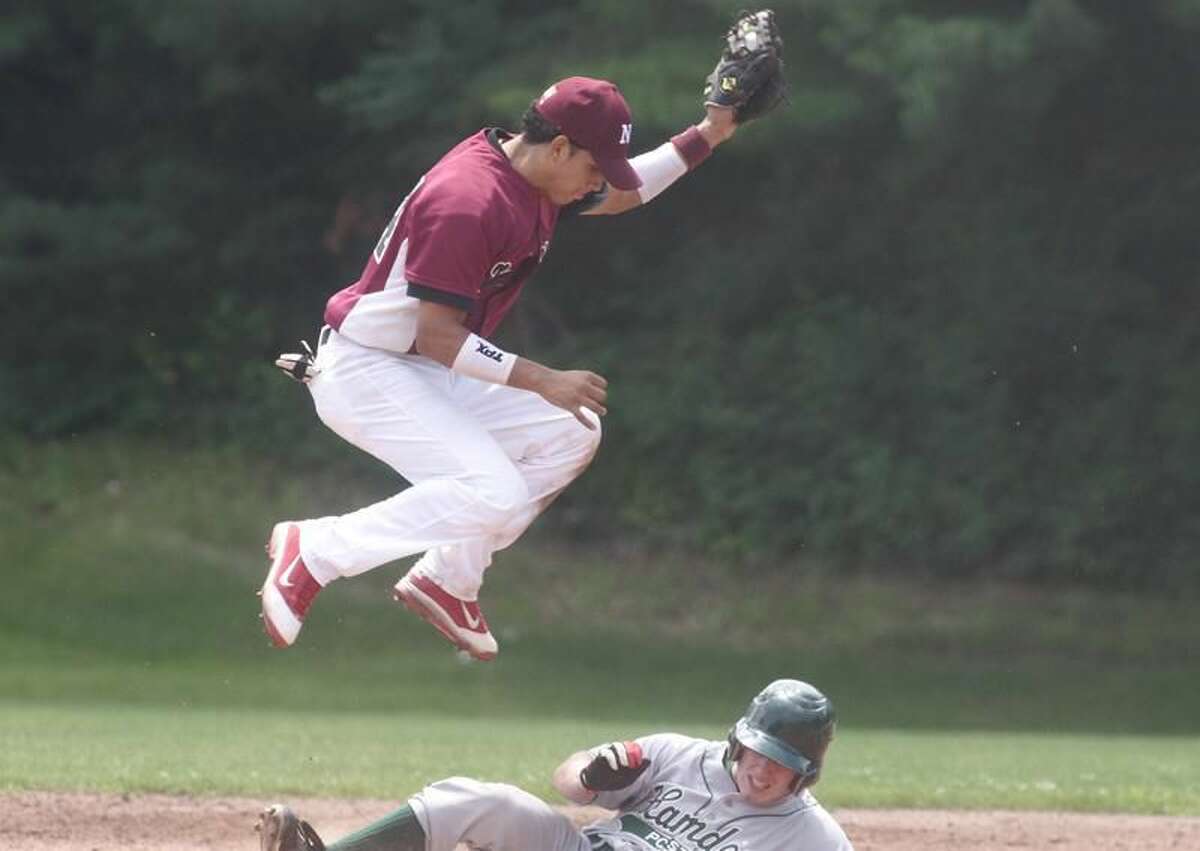 Photo by Russ McCreven North Haven shortstop Edison Rodriguez leaps to catch the ball while a Hamden runner slides under him in a recent game.