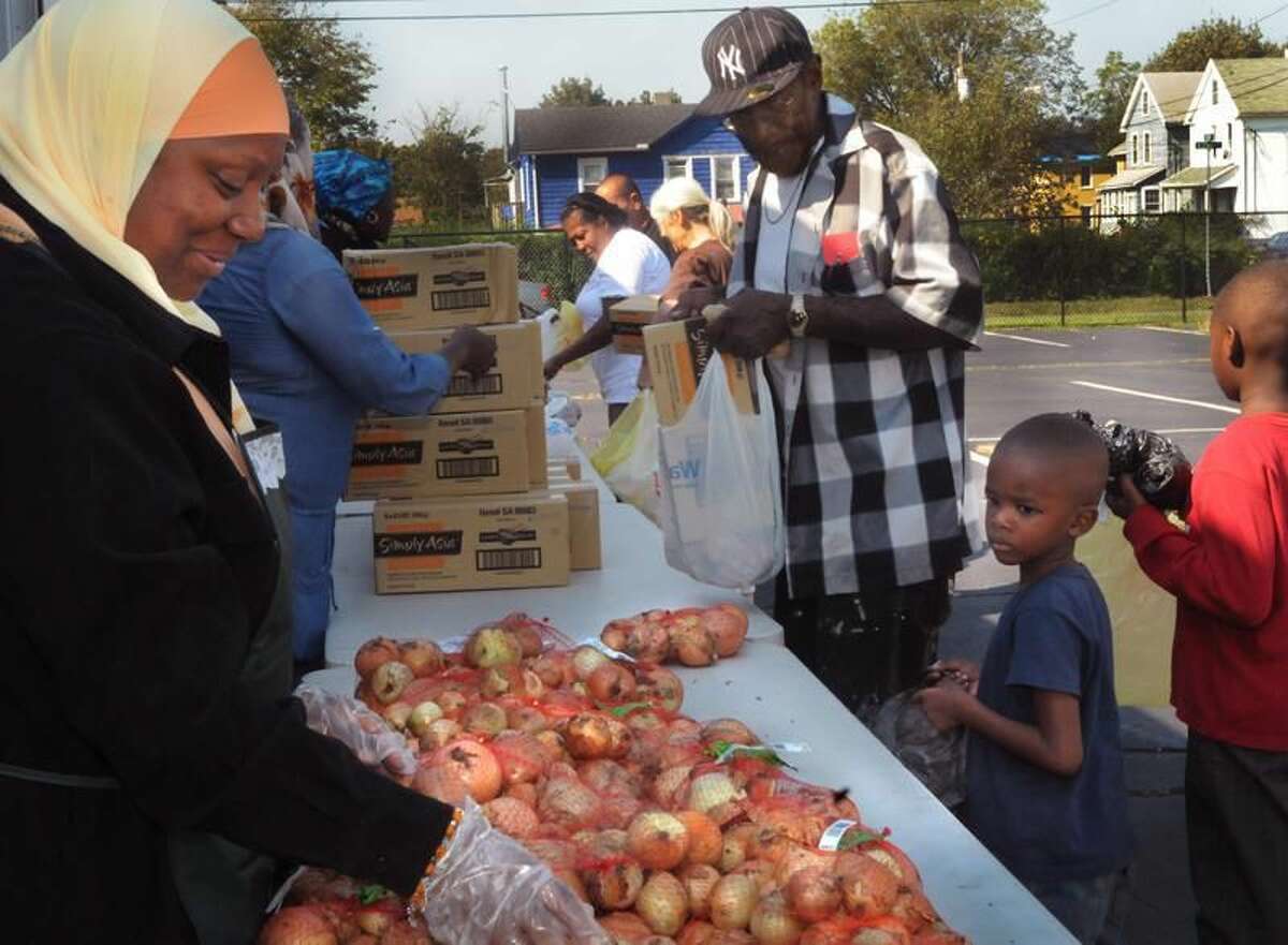 Photo by Melanie Stengel Volunteer Khadijah Mohammed, left, helps distribute food from the Connecticut Food Bank Truck Friday. Collecting groceries are, from left, Curtis Douglas, Jaihaziel Garrett, 5, and Kahanyjal Garrett, 9. The truck brought food to the Abdul-Majid Karim Hasan Islamic Center in Hamden.