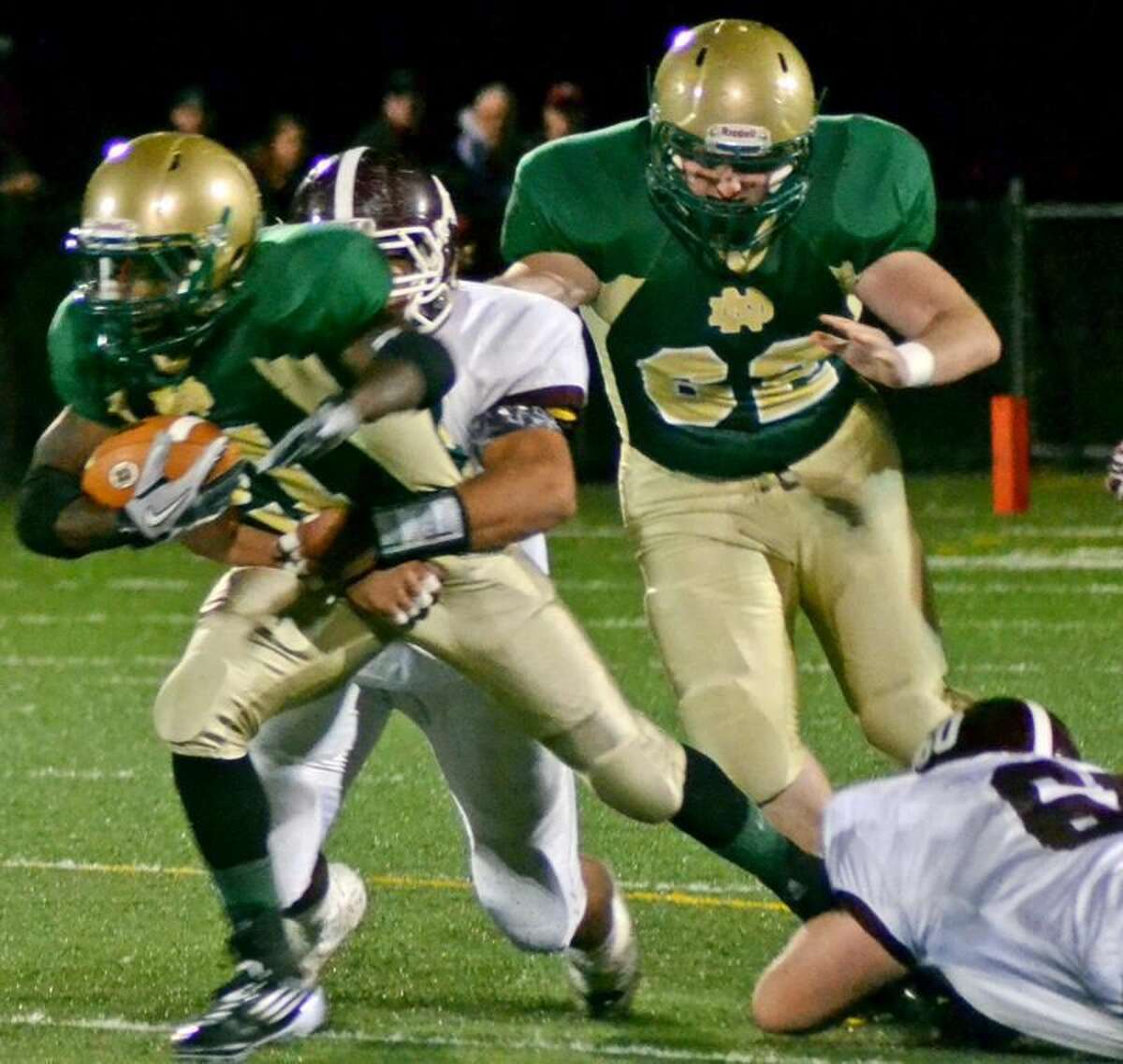 Photo by Sean Meenaghan/Register Notre Dame-West Haven running back Shawndel Evans fights for extra yards while North Haven's Andrew Savenelli tries to take him down in the Green Knights' 27-12 victory Friday night.