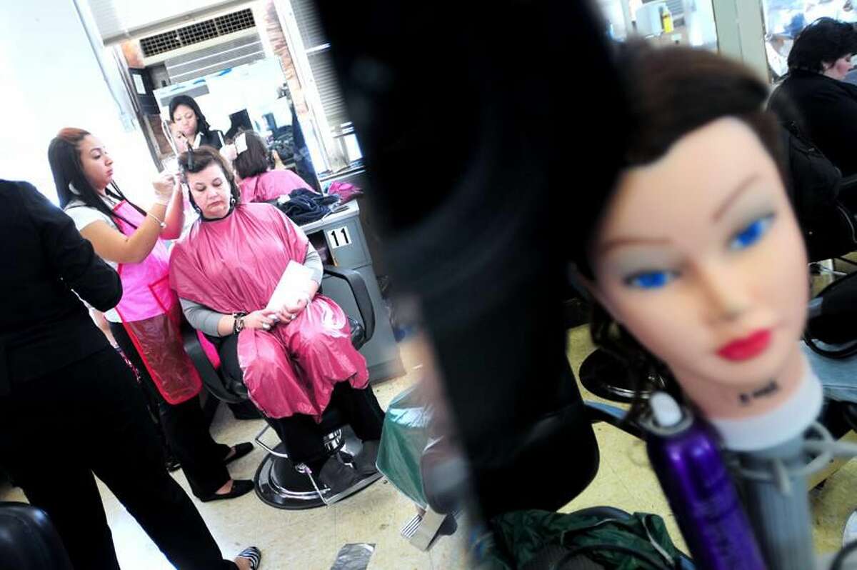 Sulaina Rodriguez, far left, 17, adds highlights to the hair of Joan Oriol in the Cosmetology and Barbering Department at Eli Whitney Technical High School in Hamden. Oriol is among a group of DCF program foster mothers from Meriden being treated to a day of pampering at the school. Arnold Gold/Register