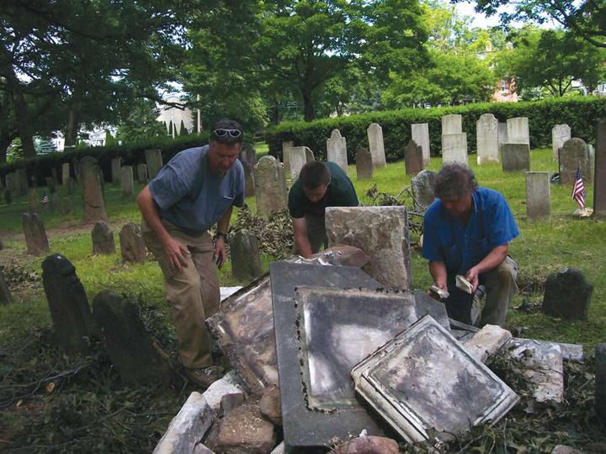 Photo by Lynn Fredricksen Martin Johnson, of Monument Conservation Collaborative, and his crew examine the rubble of the Benjamin Trumbull monument damaged when a 152-year-old black oak tree crashed into the Ancient Cemetery on the Green recently.