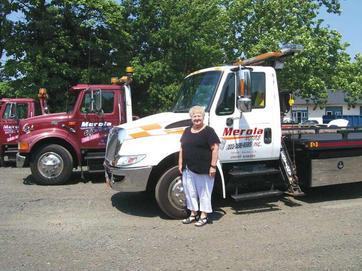 Photo by Lynn Fredrickson Mary Jane Mulligan stands with three of the trucks she and her family own through their business, Merola Motors.