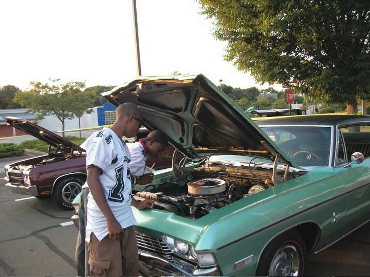 Photo by Lynn Fredricksen New Haven residents Dezjon Streater (leaning into car) and Justin Nelson, both students at Eli Whitney Technical High School, check out a 1968 Chevrolet Impala owned by Don Scialla of Hamden at a car show and fundraiser held recently to benefit the school’s football team. Both boys are members of the team.