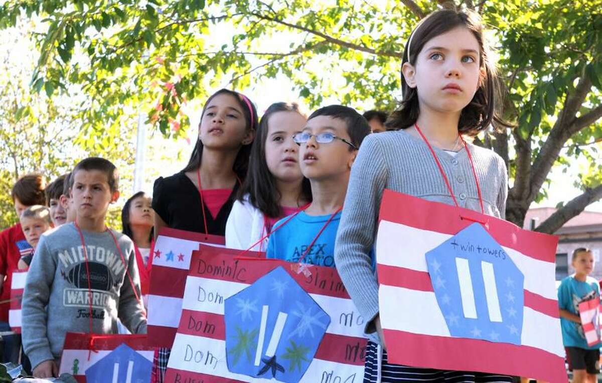 Live Oaks Elementary School second graders including Dominic Rusu with glasses and Maria Korman right during a 9/11 remembrance at the World Trade Center Memorial Garden at the school in Milford. The second graders made WTC posters in art class. Mara Lavitt/New Haven Register9/11/12