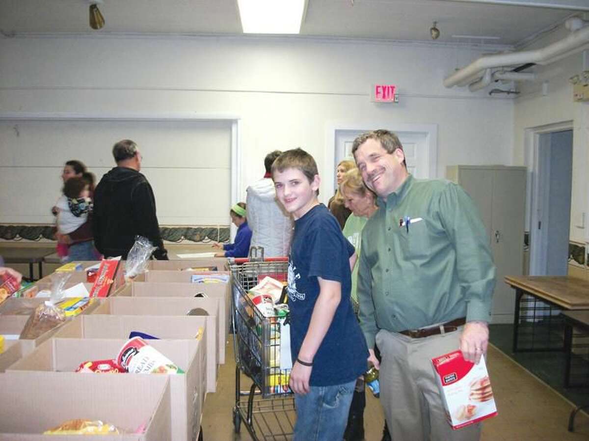 Photo by Lynn Fredricksen The Rev. Scott Morrow clowns around with parishioner Andy Romaniuk as the two work to fill boxes for the Food Bank’s annual Thanksgiving food distribution. Housed in the Congregational Church, the food bank provided for 90 needy families this Thanksgiving.