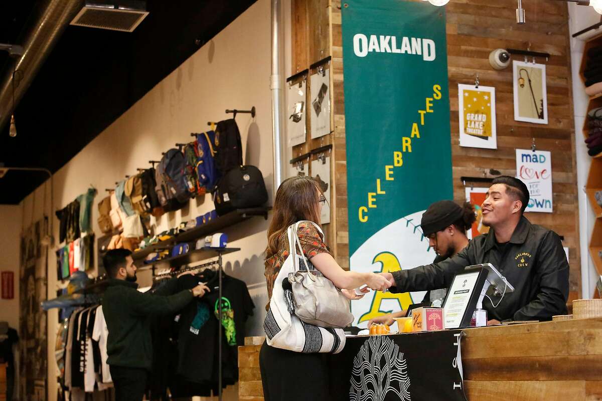 Richard Lorenzo (right), Oaklandish key holder, assists Chris Reed (right), of Oakland at the Oaklandish store on Broadway on Monday, October 14, 2019 in Oakland, Calif.