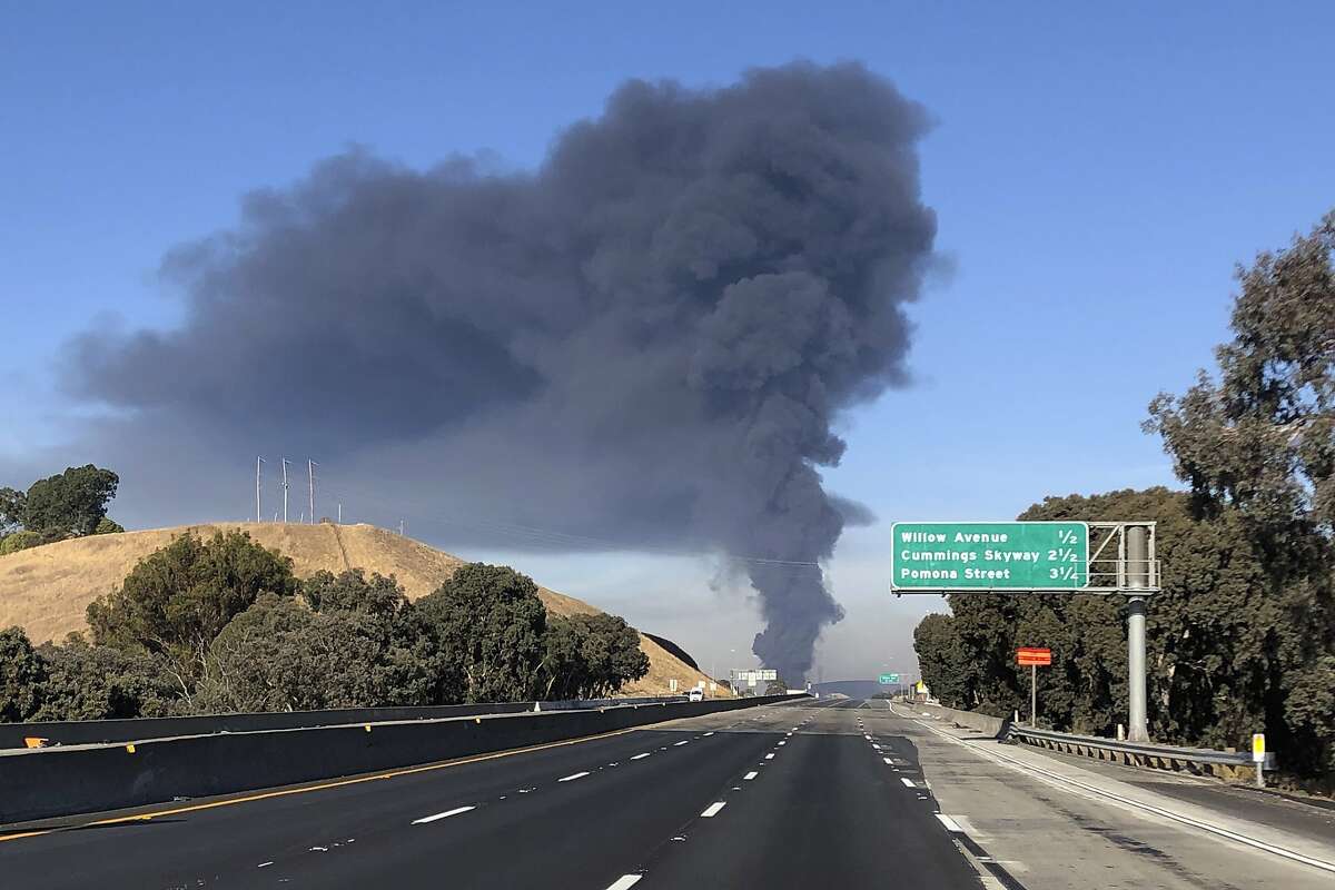 Interstate 80 is closed as a fire at an oil storage facility burns in the background Tuesday, Oct. 15, 2019, in Rodeo, Calif. A fire burning at NuStar Energy LP facility in Crockett, Calif., in the San Francisco Bay Area prompted a hazardous materials emergency that led authorities to order the residents of two communities, including Rodeo, to stay inside with all windows and doors closed. Contra Costa Fire Department spokesman Steve Hill said that an hour into battling the blaze, firefighters seemed to be making progress and were continuing to keep adjacent tanks cooled with water.
