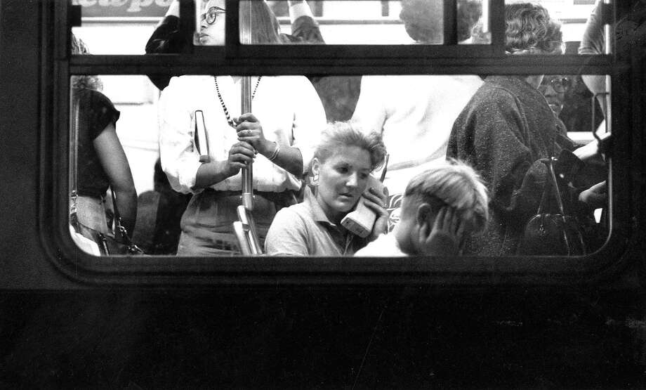 Woman in a crwded bus in San Francisco uses a cellular phone to commmunicate after the Loma Prieta earthquake October 17, 1889  Photo ran 10/18/1989 P.A6, Photo: Steve German / The Chronicle 1989