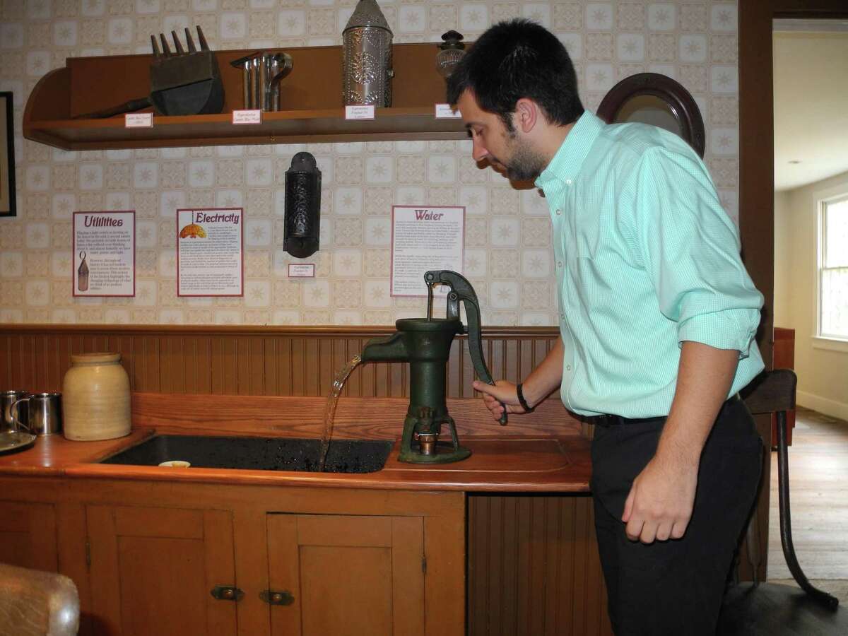 Associate curator Nick Foster demonstrates a water pump in the Wilton Historical Society’s 1910 kitchen.