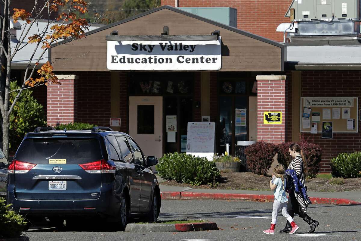 In this Oct. 9, 2019, photo, people walk near an entrance to the Sky Valley Education Center in Monroe, Wash. A lawsuit filed on behalf of several families and teachers claims that officials failed to adequately respond to PCBs, or polychlorinated biphenyls, in the school. (AP Photo/Ted S. Warren)