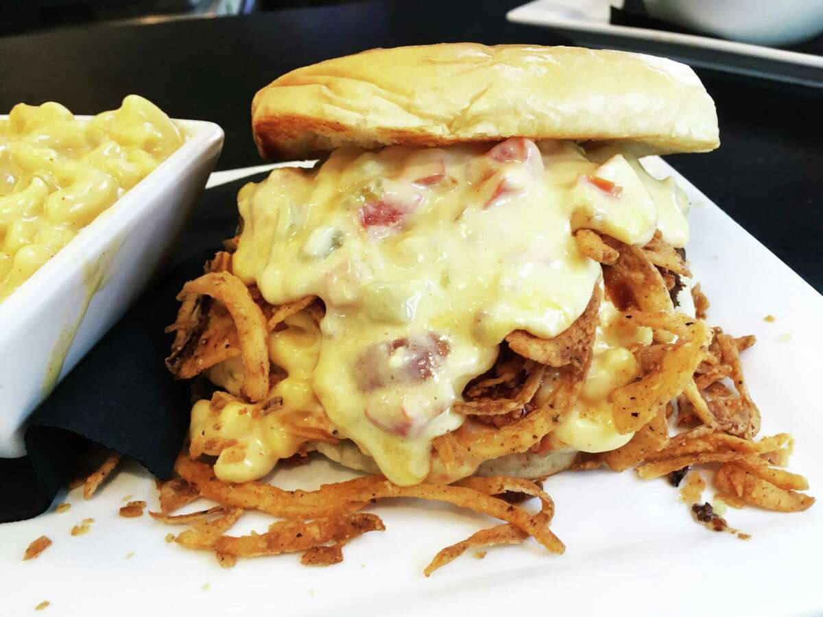 The Pour Over burger comes with melted queso that is designed to top a layer of crispy onion strings and mac and cheese over the burger patty.