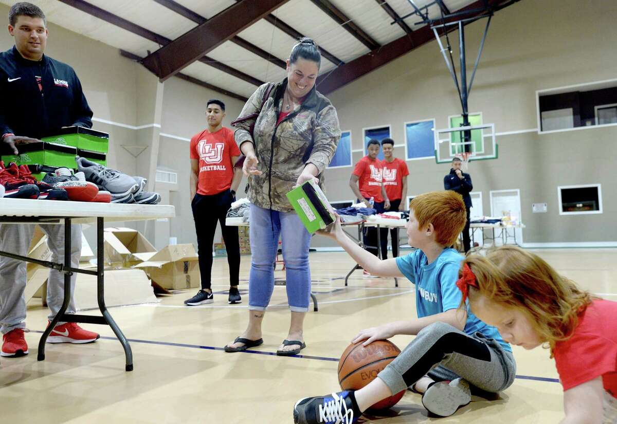 Tammy Ray hands her son Gage the box for his new gym shoes as they and Evangeline Ray stop to pick up needed items during Lamar basketball's clothing and shoe give-away to those affected by flooding at First Baptist Church in Hamshire Wednesday. Photo taken Wednesday, October 16, 2019 Kim Brent/The Enterprise