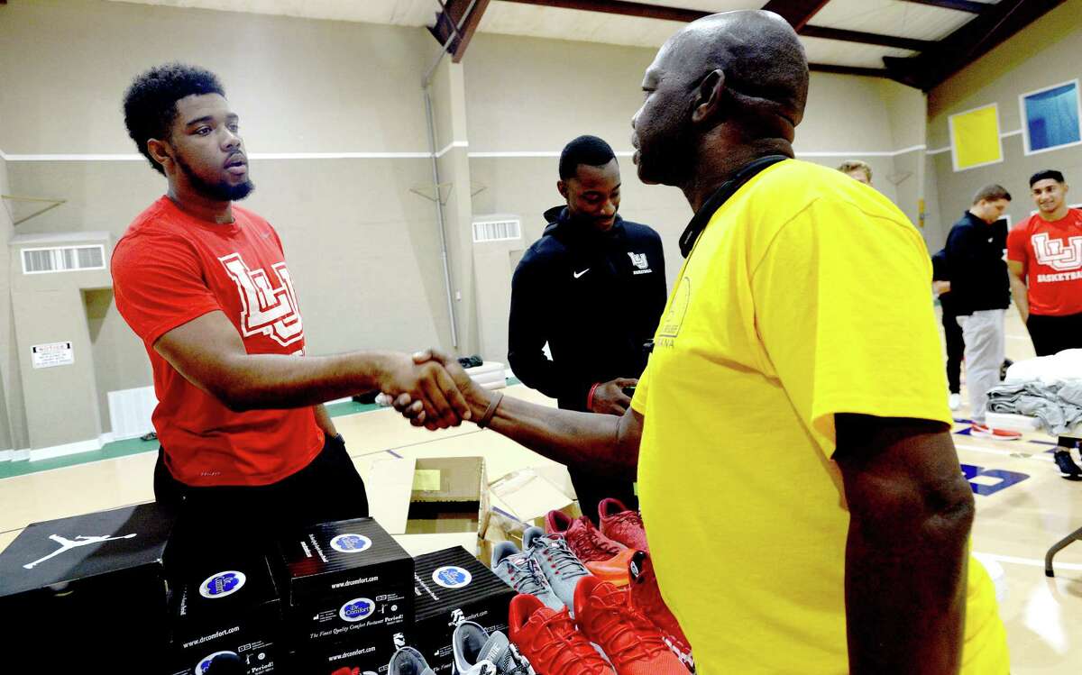 Lamar basketball's Avery Sullivan gets a handshake from Disaster Relief Louisiana volunteer Keith Johnson as he and teammate Kain Harris man station during a clothing and shoe give-away to those affected by flooding at First Baptist Church in Hamshire Wednesday. Photo taken Wednesday, October 16, 2019 Kim Brent/The Enterprise