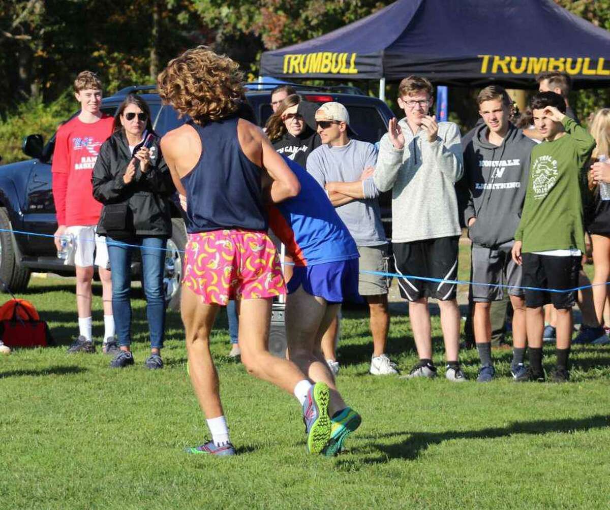 Wilton’s Davis Cote, left, helps Danbury’s Aidan Byrne across the finish line at the FCIAC championships on Tuesday at Waveny Park in New Canaan.
