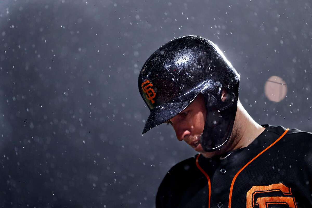 San Francisco Giants' Buster Posey waits to bat as rain falls during Bay Bridge Series game against Oakland Athletics at Oracle Park in San Francisco, Calif., on Monday, March 25, 2019.