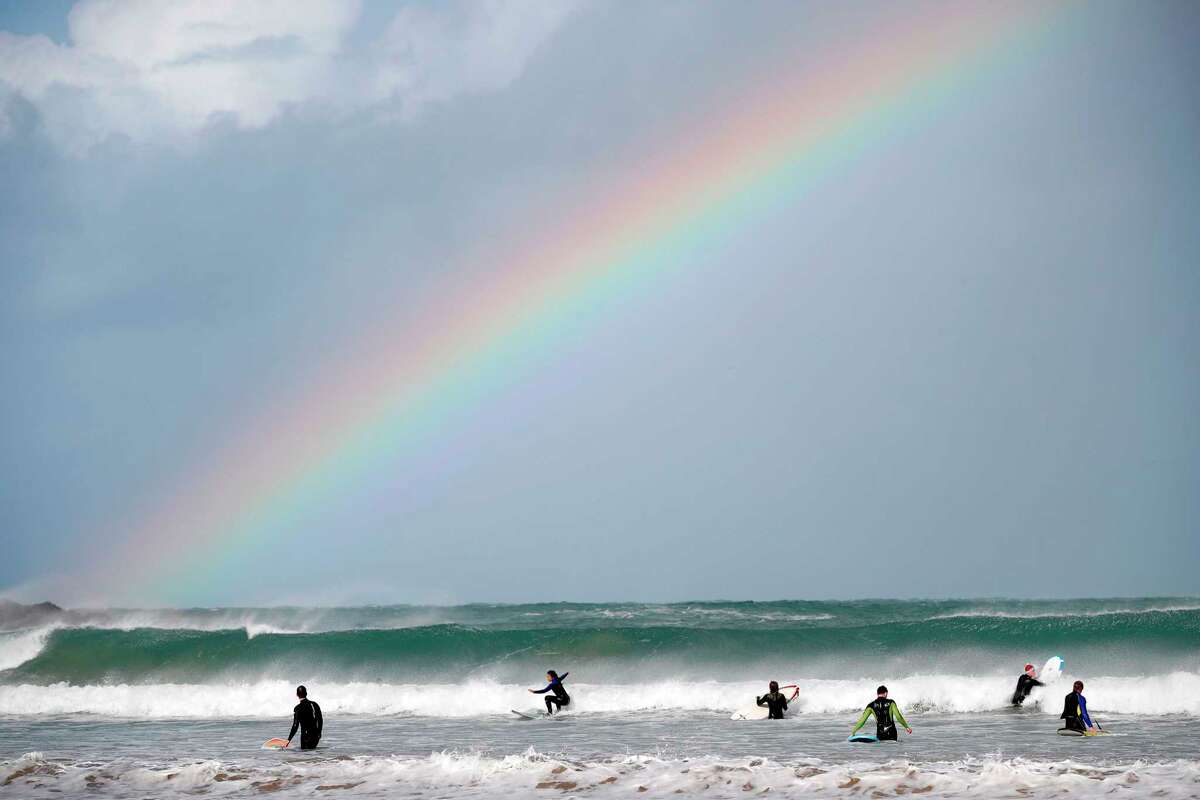 A rainbow is seen over surfers and bodyboarders at Towan Beach in Newquay, southwest England.