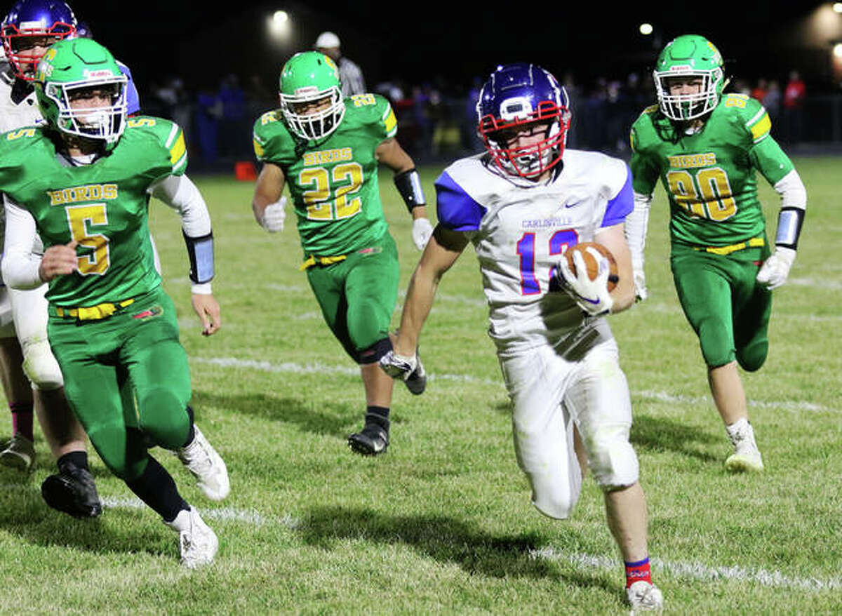 Carlinville’s Joe Leiws (12) breaks away for a 38-yard run with Southwestern’s Gavin Day (5), Jacob Fisher (22) and Pauly Garrett (20) in pursuit early in the third quarter Friday night at Knapp Field in Piasa.
