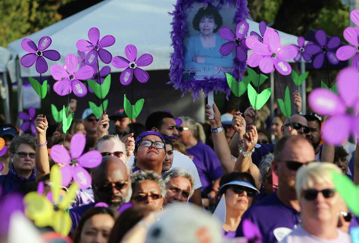 Purple flowers are held up during a somber moment to honor loved ones who have died from Alzheimer's disease as thousands of people gather at Palo Alto College to take part in the “Walk to End Alzheimer's” event on Saturday, Oct. 19, 2019.