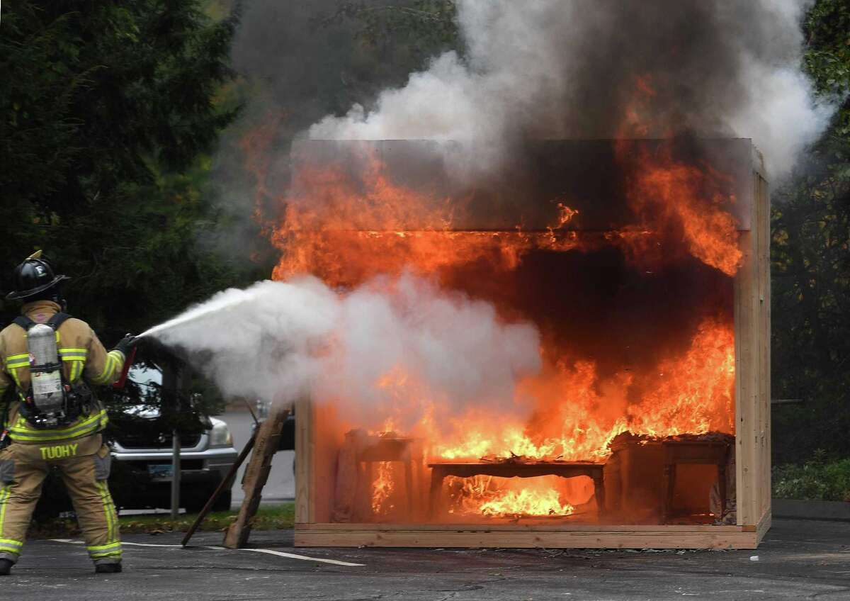 A Trumbull firefighter demonstrates the inability of a home fire extinguisher to put out a large fire during a live fire demonstration at Trumbull Volunteer Fire Co. #1 at 860 White Plains Road in Trumbull on Sunday. The demonstration was one of many events at a daylong open house at the station. More photos, A5.