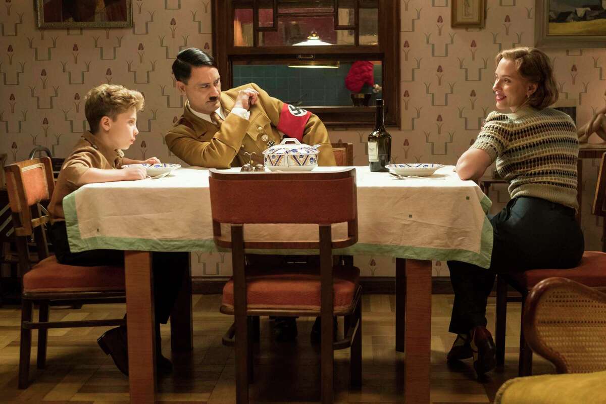 This image released by Fox Searchlight Pictures shows, from left, Roman Griffin Davis, Taika Waititi and Scarlett Johansson in a scene from the WWII satirical film "Jojo Rabbit." (Kimberley French/Fox Searchlight Pictures via AP)