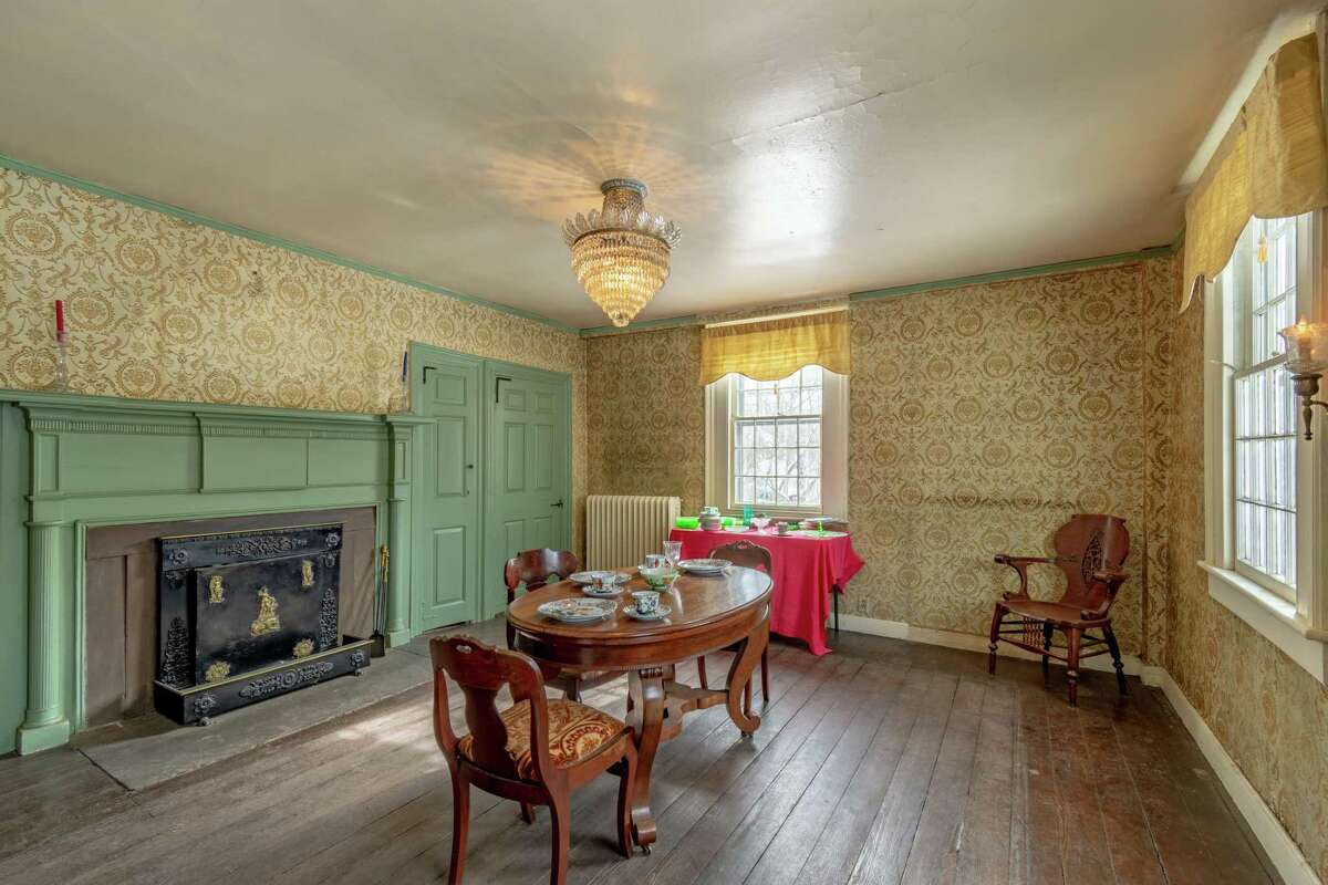 The formal dining room features a large fireplace, period wallpaper, and wide-planked wood flooring.