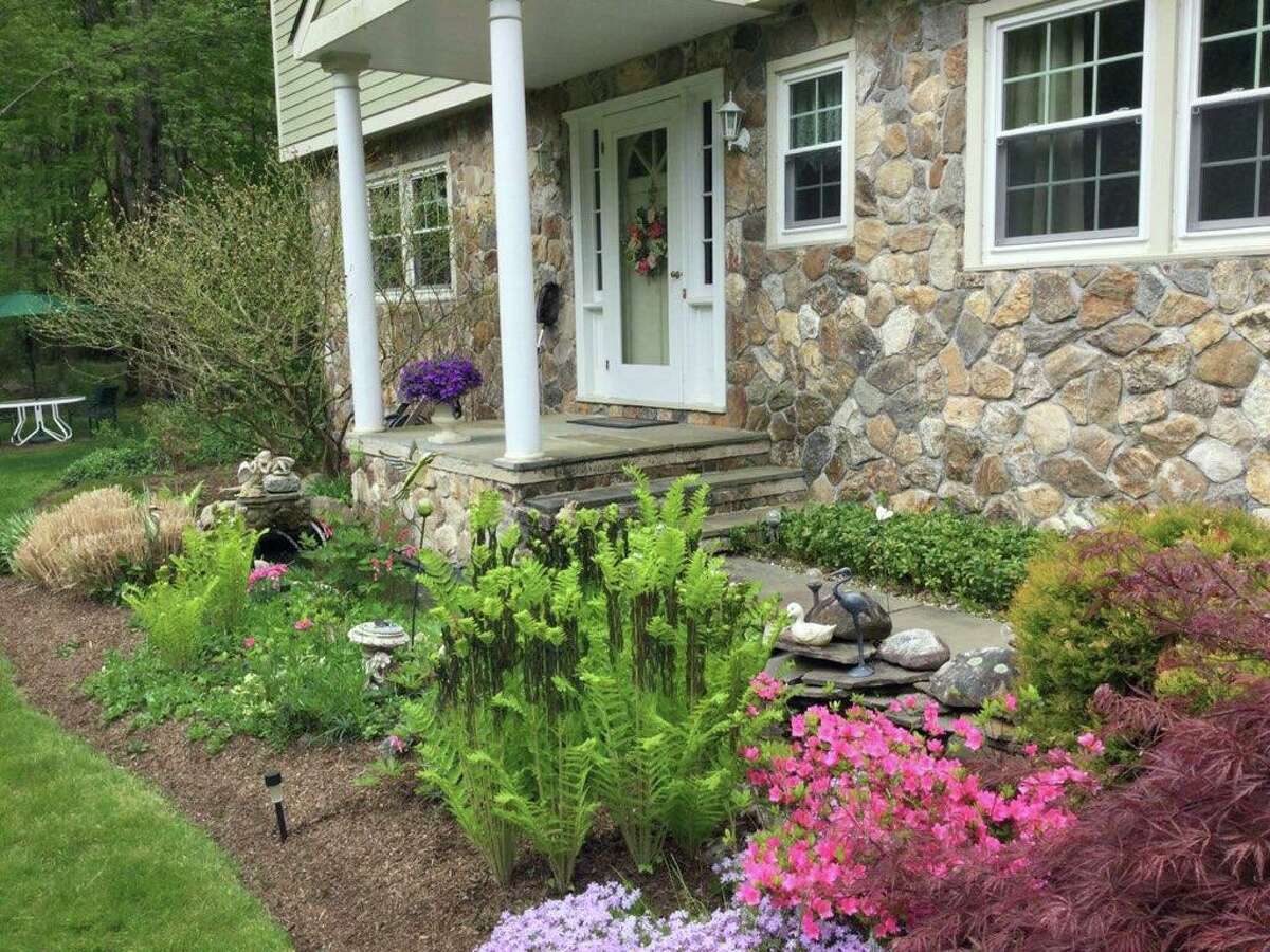 The property has attractive landscaping including roses, azaleas, ferns, peonies, hostas, hydrangeas, a Japanese maple, and seagrasses.