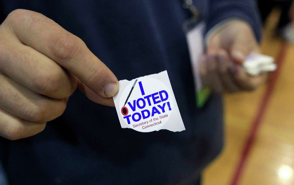 A poll worker shows a "I Voted Today" sticker
